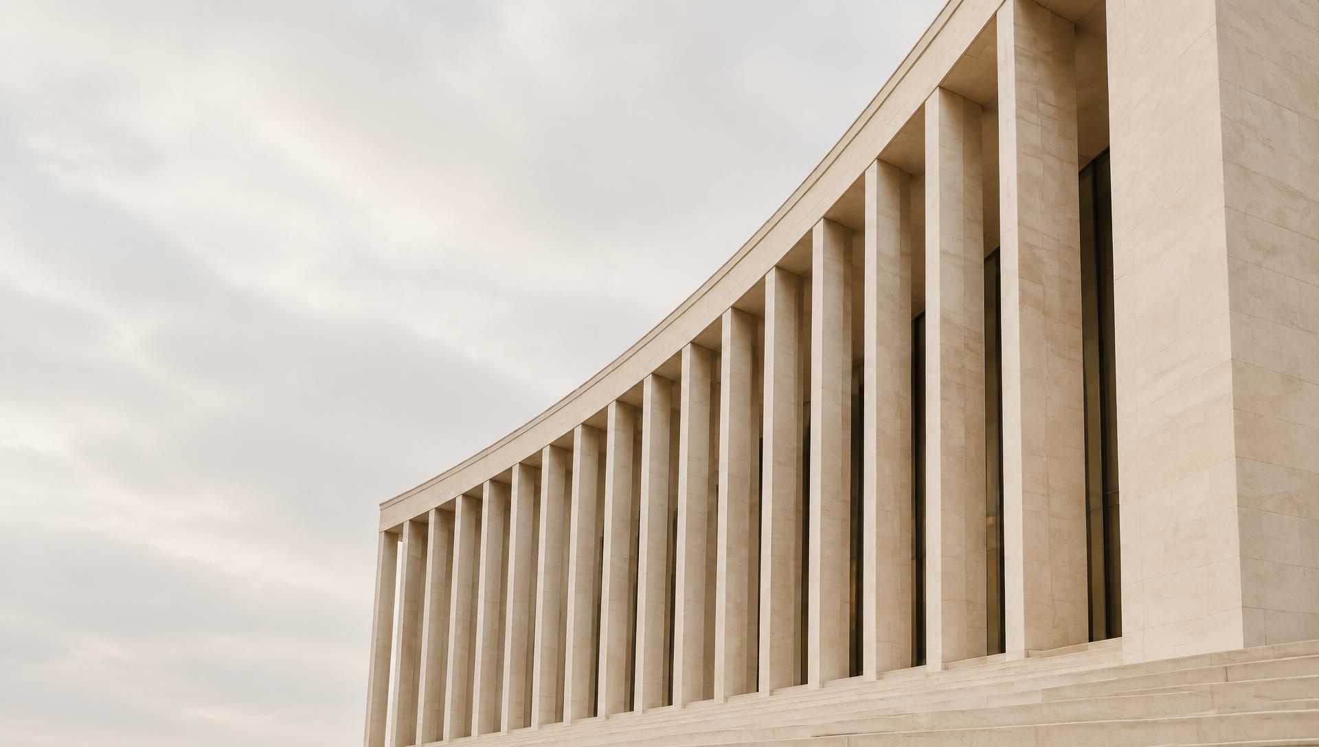 Quiet, sculptural limestone architecture with a rhythm of vertical columns
